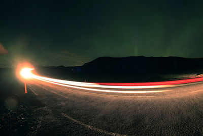 Light trails on road against sky at night