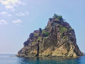 Rock formation in sea against sky