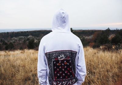 Rear view of man standing on field against sky