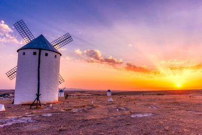 Traditional windmill against sky during sunset