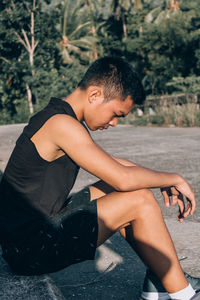 Side view of young man sitting outdoors