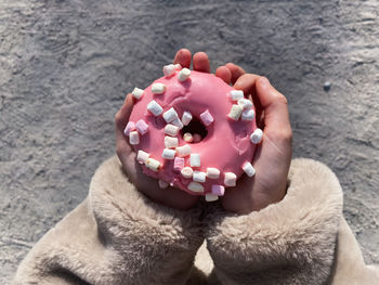 Donut with marshmallows is on child hand