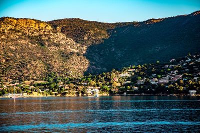 Scenic view of sea by townscape against sky