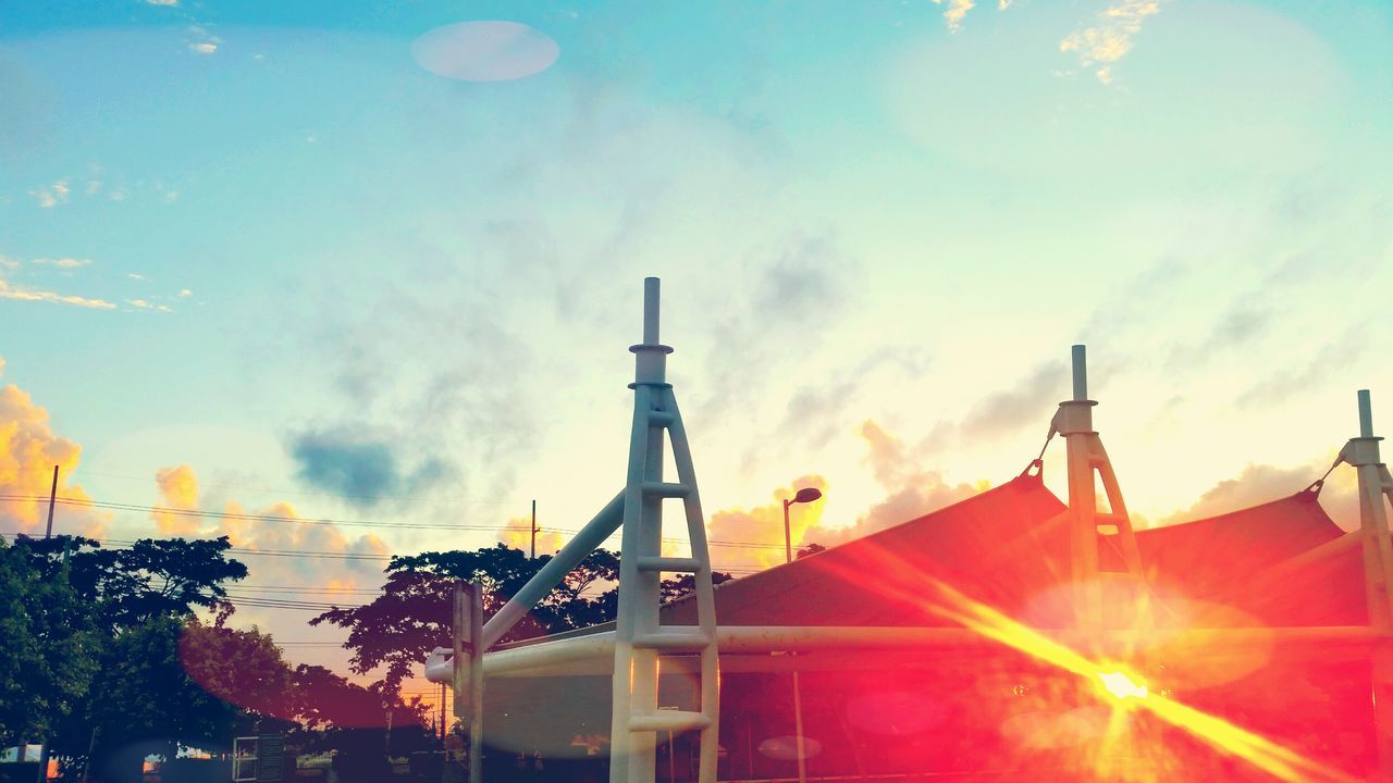 low angle view, sky, architecture, built structure, building exterior, cloud - sky, cloud, cloudy, sunset, sunlight, no people, outdoors, high section, building, day, tower, metal, protection, lighting equipment, silhouette