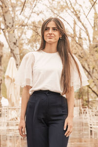 Portrait of young woman standing against tree