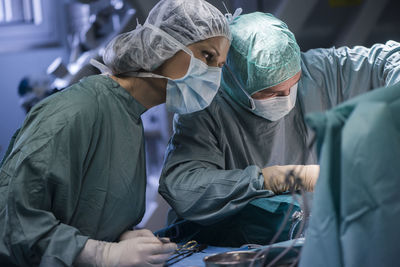 Neurosurgeon with nurse closing operation wound