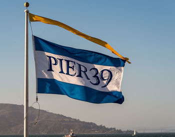 Low angle view of flag against blue sky