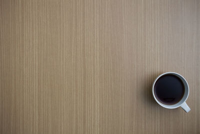 A white coffee cup on a wooden table with copy space.