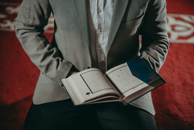 Midsection of man reading book