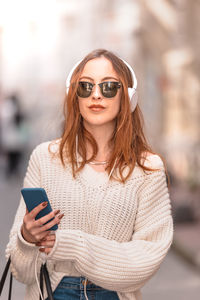 Beautiful young woman using mobile phone outdoors