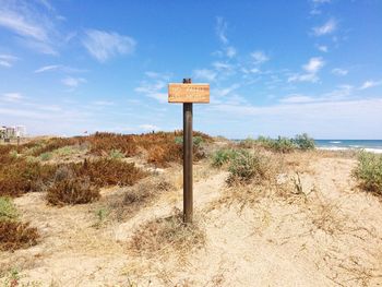 Information sign on beach against sky