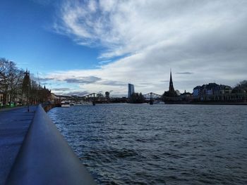 Scenic view of river by buildings against sky