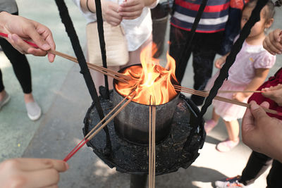 Midsection of people holding burning incense sticks for worship in a chinese temple.