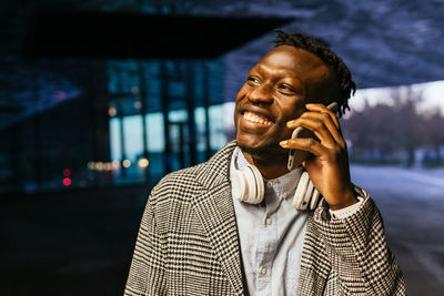 Smiling young man using mobile phone in city