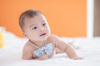 Cute baby boy lying on bed at home