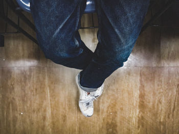 Low section of man standing on hardwood floor