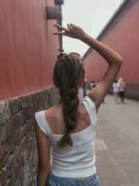 Rear view of woman standing against wall