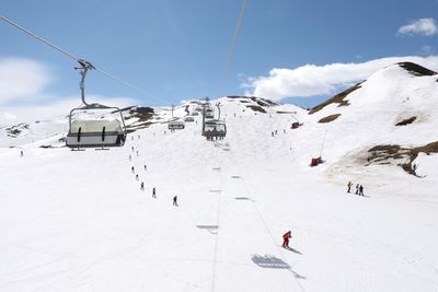 Ski lift on snowcapped mountains against sky