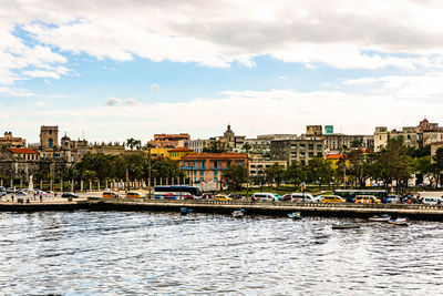 View of buildings at waterfront against cloudy sky