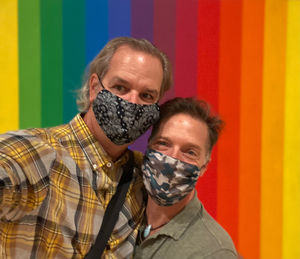 Portrait of smiling friends wearing mask standing against colored background