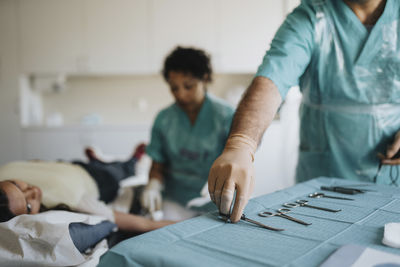 Male surgeon arranging surgical equipment on table in hospital