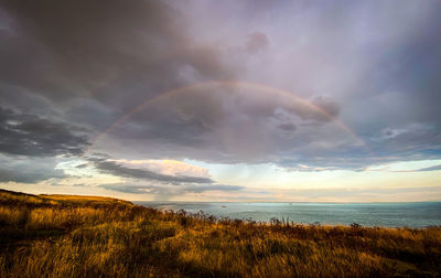 Scenic view of sea against rainbow in sky