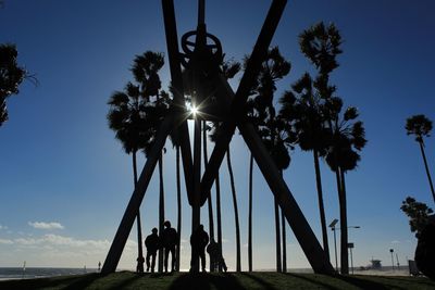 Low angle view of silhouette people walking on palm trees