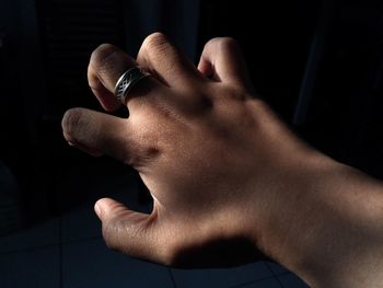 Cropped hand of woman wearing ring against black background