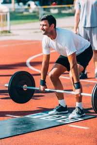 Man lifting dumbbell on running track