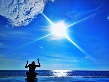 Silhouette woman in sea against bright sun