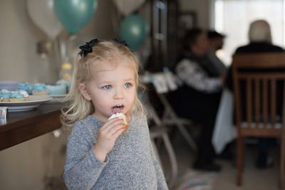 Close-up of cute girl eating food at home