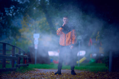 Teenage boy smoking electronic cigarette in park