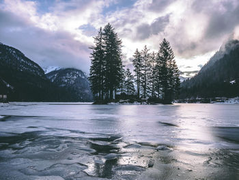Frozen lake against mountains and sky during winter