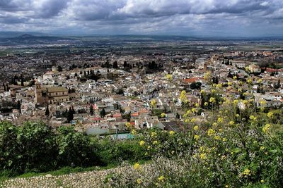 Aerial view of cityscape against cloudy sky