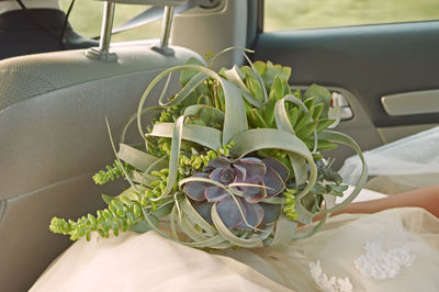 Midsection of bride holding bouquet while sitting in car