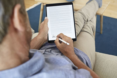 Mature man signing digital contract on tablet