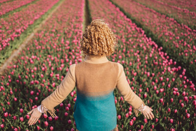Rear view of woman standing on tulip field