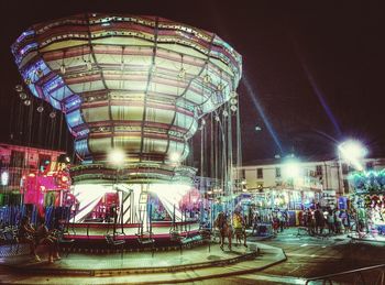 Illuminated ferris wheel against sky at night