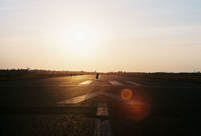 Person on road against sky during sunset