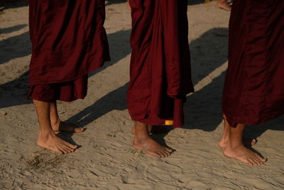 Low section of monks standing at beach