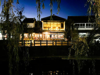 Illuminated buildings by lake against sky in city at night