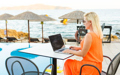 Woman using laptop at beach