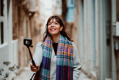 Woman holding monopod standing in alley