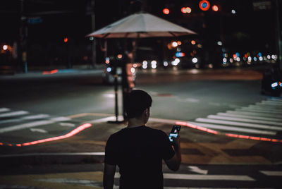 Rear view of man walking on city street at night