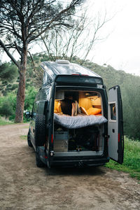 Unrecognizable travelling couple sitting inside modern camper van parked on green hilly area in summer countryside