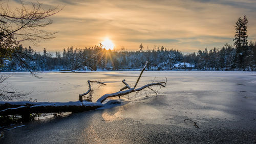 Snow covered landscape against sky during sunset