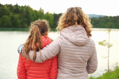 Rear view of mother with daughter standing at lakeshore