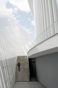 Man walking in modern building against sky