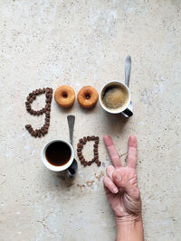 High angle view of  coffee bean  art on stone table with doughnut and hand 