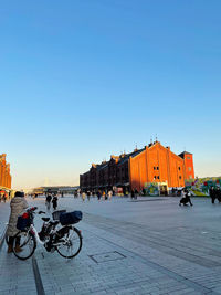 People riding bicycle on street against buildings in city